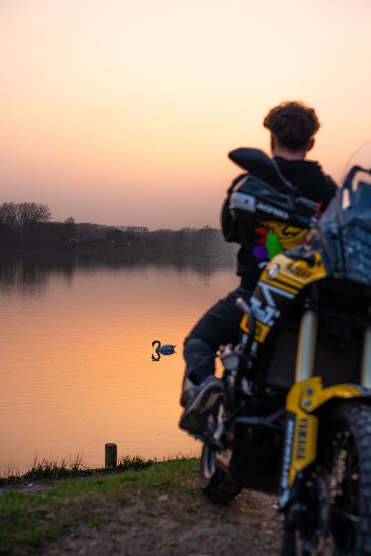 Silhouette de pilote de dos au premier plan, cygne net sur un lac miroir au coucher de soleil